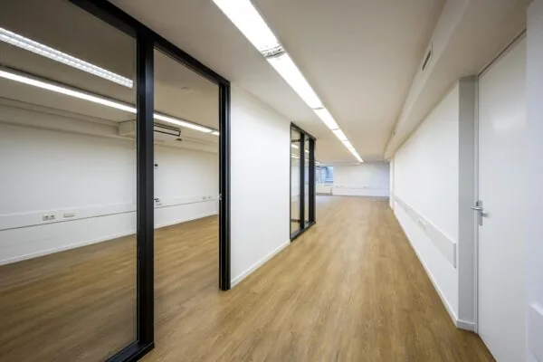 Lichte, moderne kantoorruimte aan de Prins Hendrikkade met houten vloer en glazen scheidingswanden.